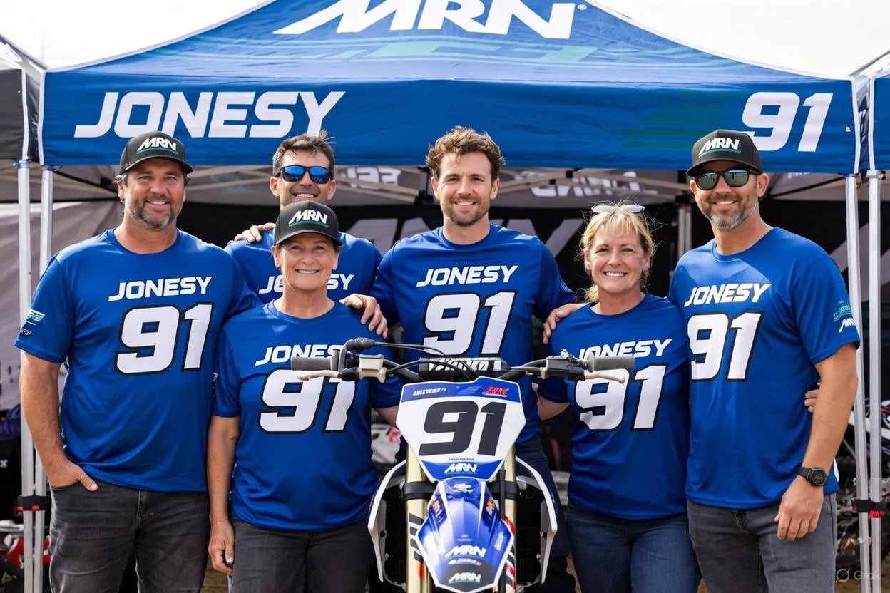 Motocross family and team wearing matching custom motocross shirts with race number under an MRN canopy tent at the track
