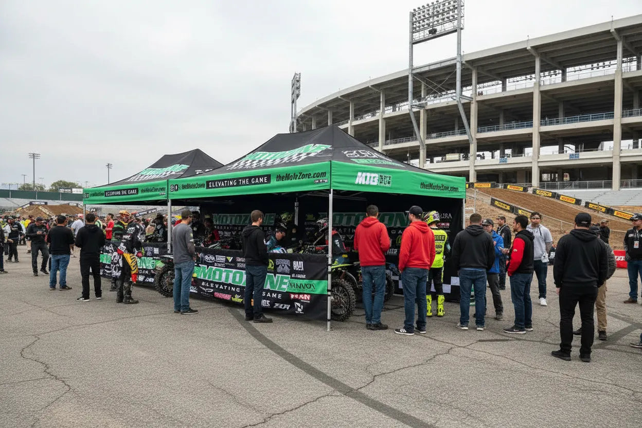 Custom pop-up canopy tent with sponsor logos at a supercross racing venue